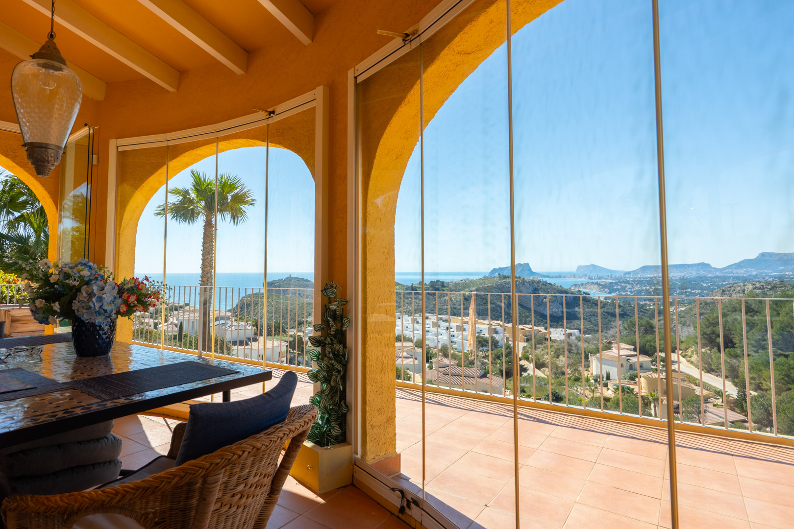 Glazed naya featuring traditional arches, beamed ceilings, and panoramic views of the Mediterranean coastline and Peñón de Ifach from the dining area.