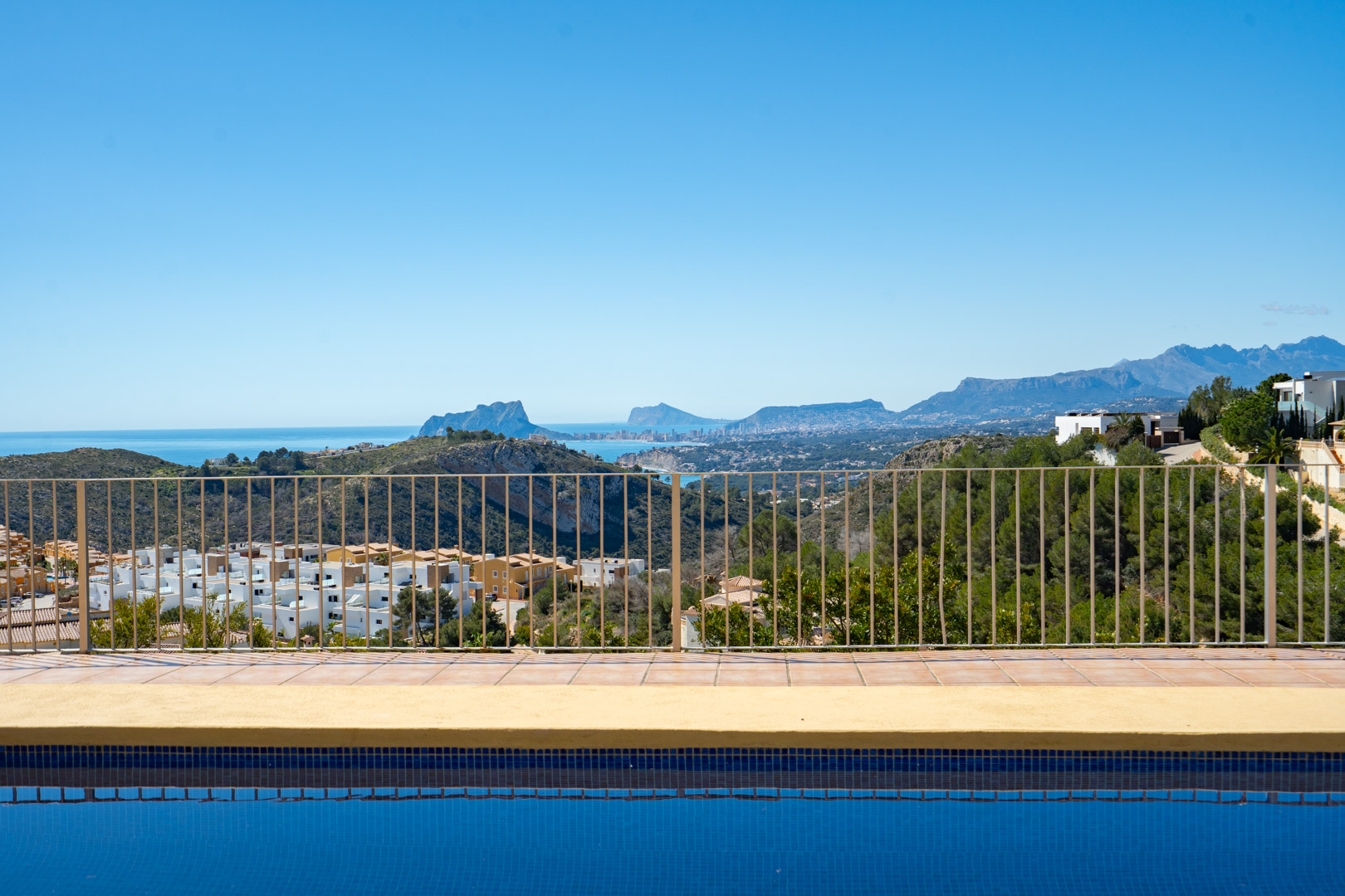 Panoramic views from the poolside terrace overlooking the Mediterranean coast, featuring the Peñón de Ifach and the distant Sierra Bernia mountain range.