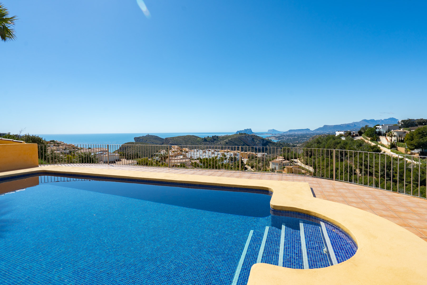 Terrace featuring a blue-tiled swimming pool with Roman steps, offering panoramic views of the Mediterranean coastline, Calpe, and the Bernia mountains.