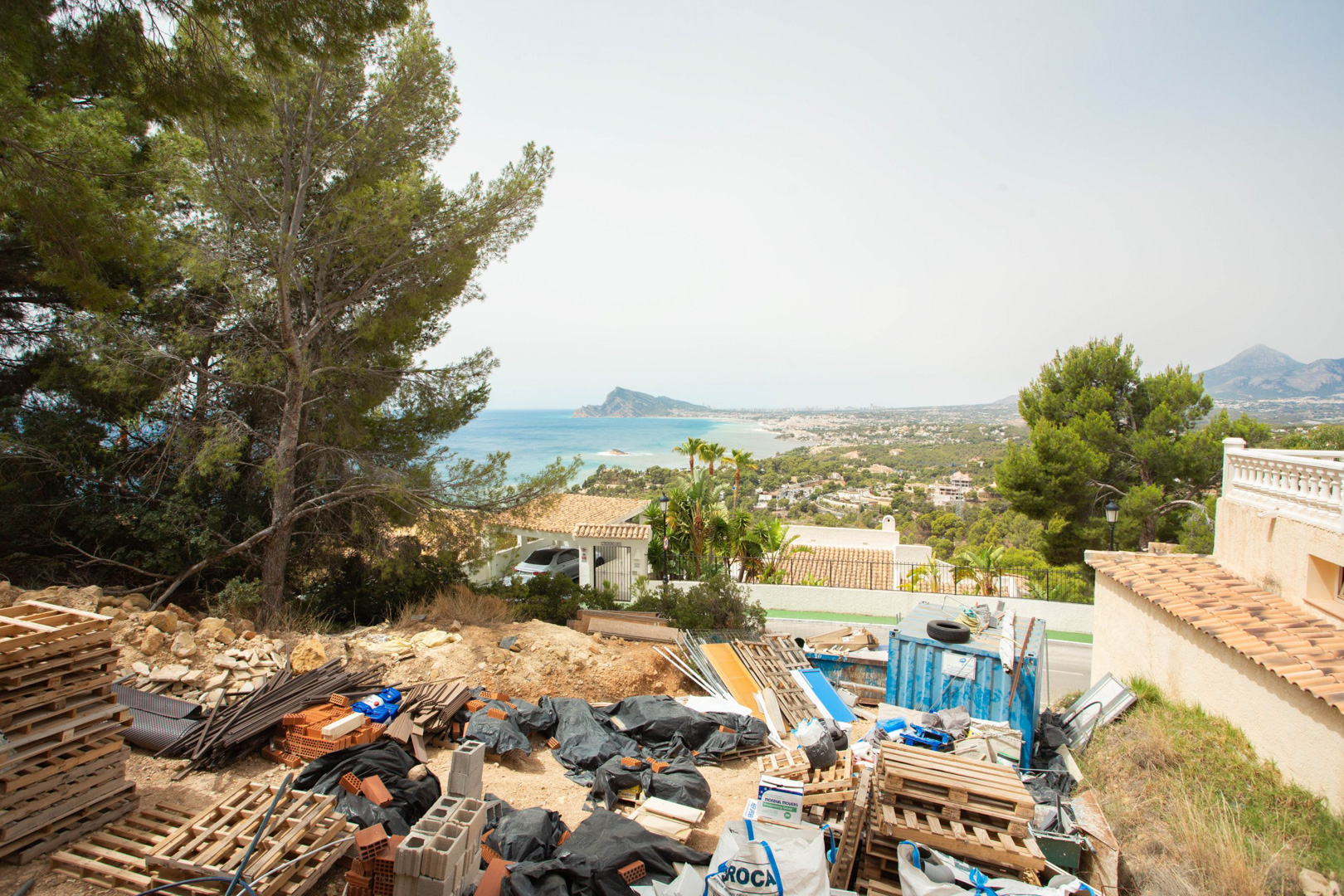 Elevated view from the Altea Hills plot, featuring construction materials and a clear panorama of the Mediterranean Sea and Altea coastline.