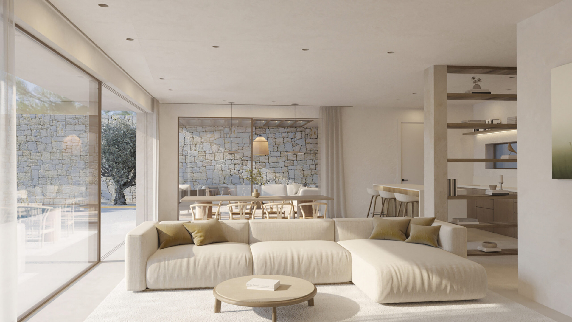 Spacious living area featuring a light sectional sofa and round coffee table. Large glass doors reveal an exterior patio with a natural stone wall and an ancient olive tree.