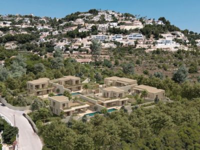 Aerial view of a modern residential complex featuring light-toned villas with private pools, nestled into a green, tree-covered hillside.