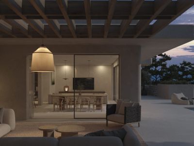 An inviting outdoor living area with contemporary sofas and a fabric pendant lamp, seamlessly connecting to an elegant indoor dining space with mountain views at dusk.