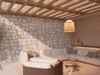 Outdoor lounge area featuring a natural stone wall, wooden pergola, and a large L-shaped sofa. Ambient lighting from a hanging pendant complements the modern design.