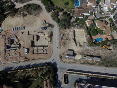 Aerial view of a residential development site in Jávea, showing concrete foundations laid for new villas and excavated plots alongside existing homes with private pools.