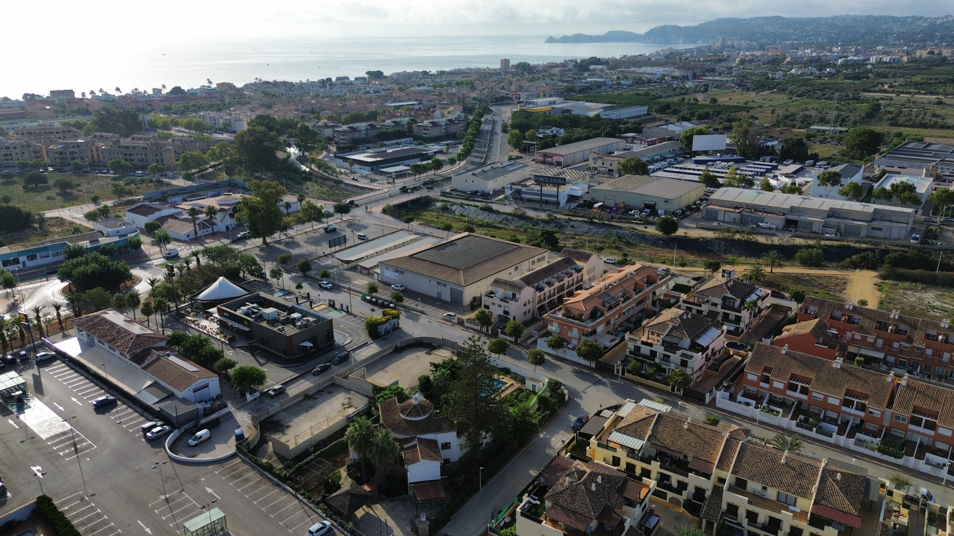 Aerial view of Jávea featuring residential and commercial buildings with the Mediterranean Sea in the background.