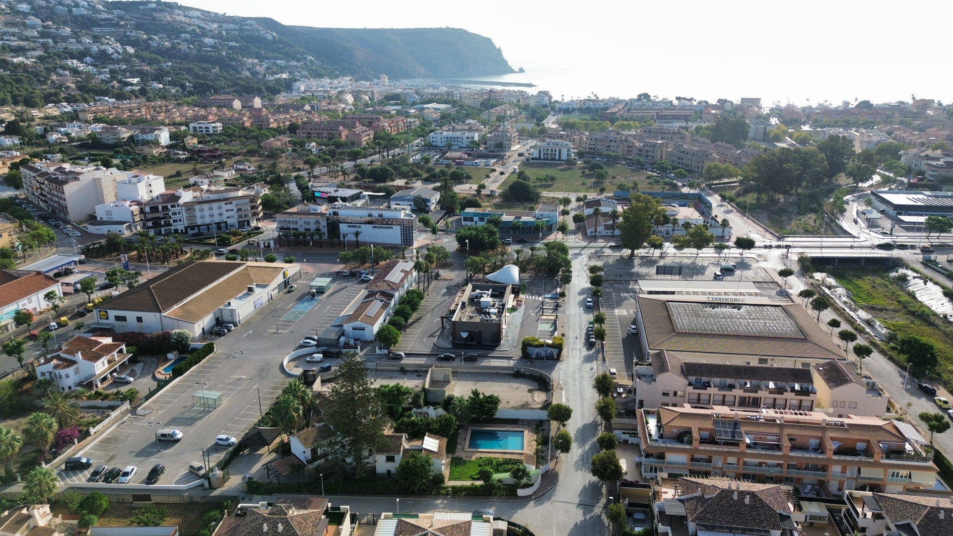 Aerial view of the property near amenities, featuring a private pool and ample parking.