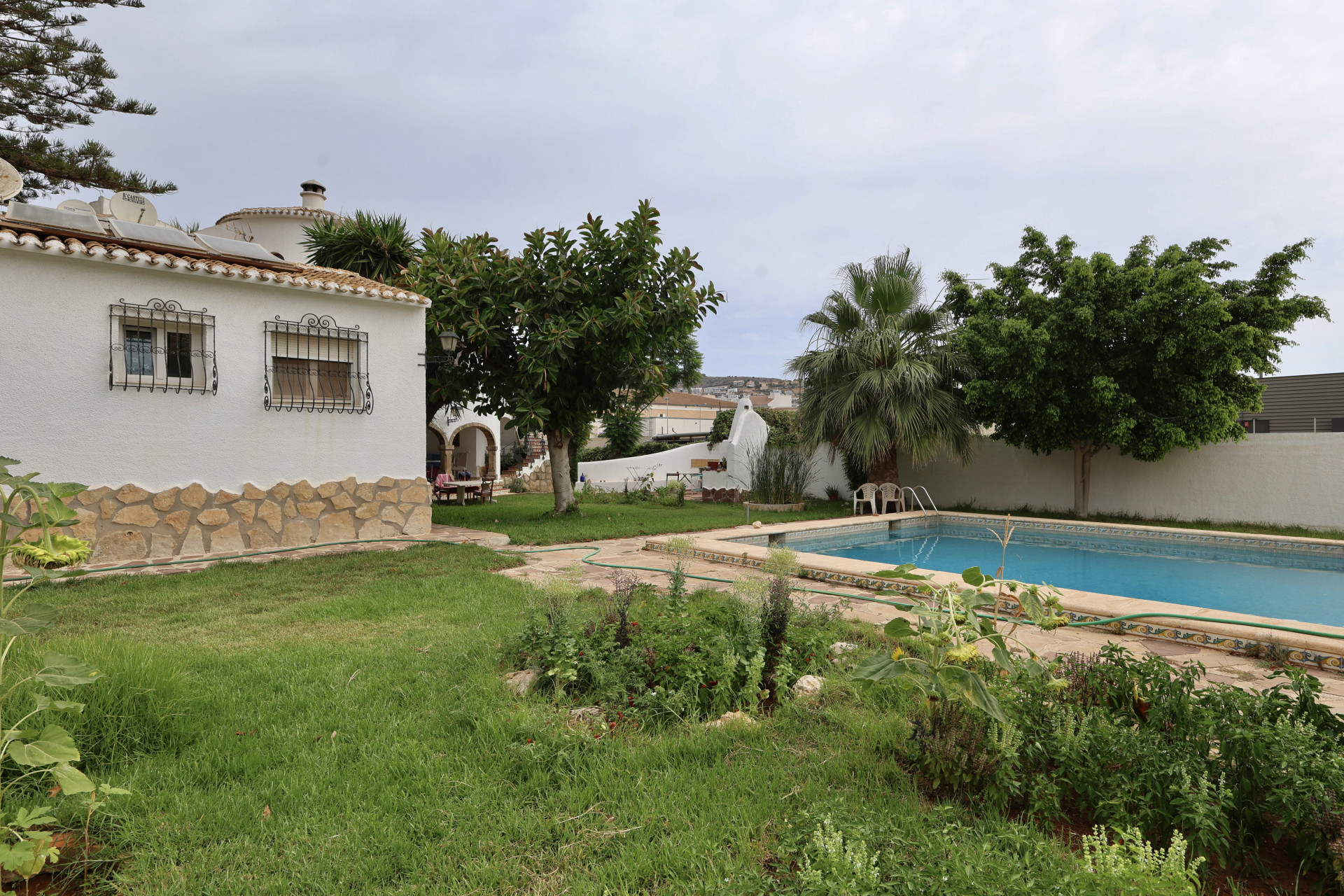 Garden view with rectangular pool and villa facade featuring stone detailing.