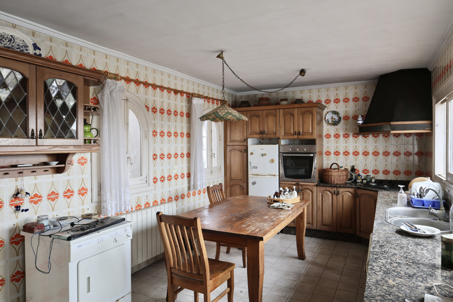 Kitchen with patterned tiles and wooden furniture, in need of renovation.