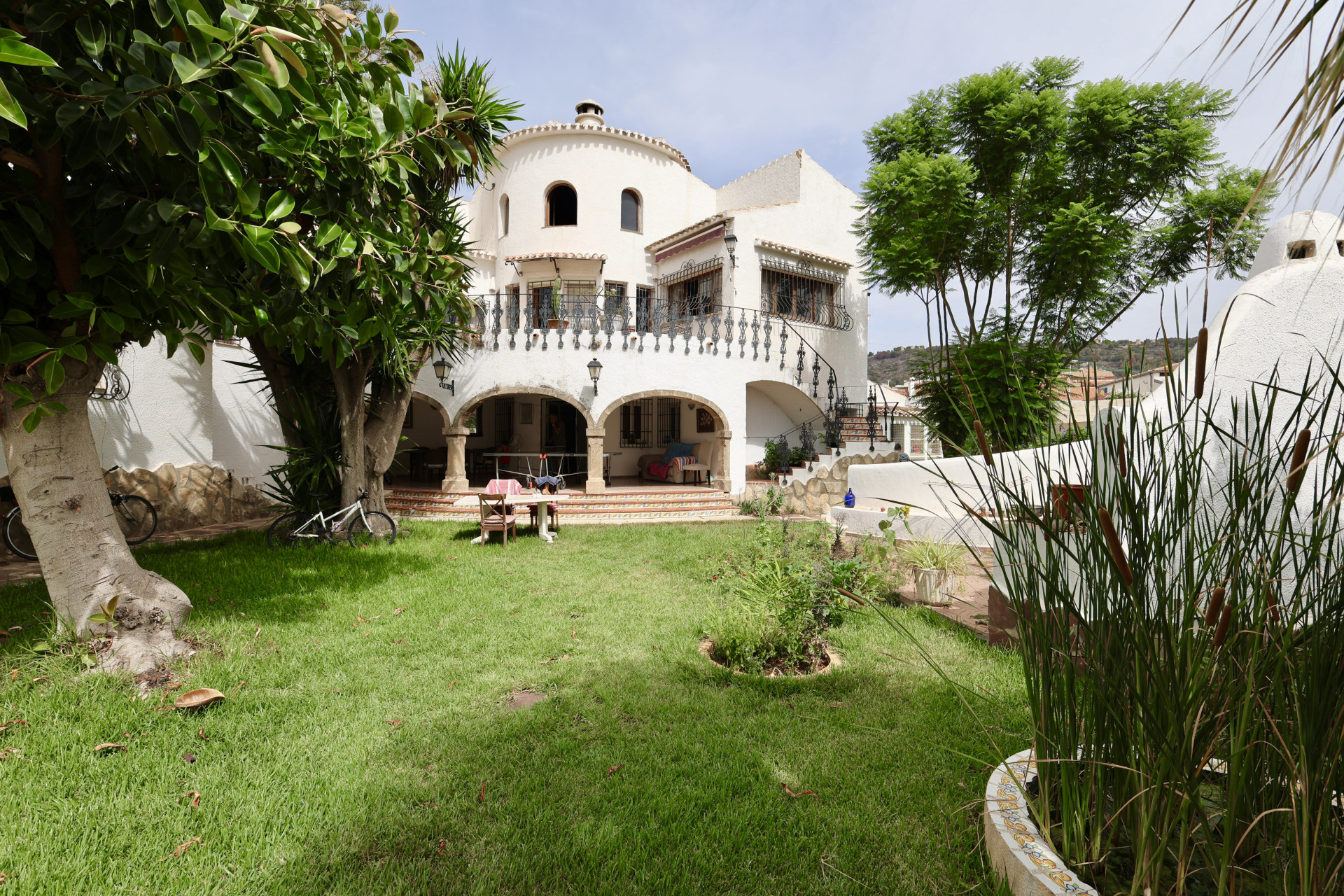 View of the front yard with lawn, greenery, and the white facade of the Javea villa.