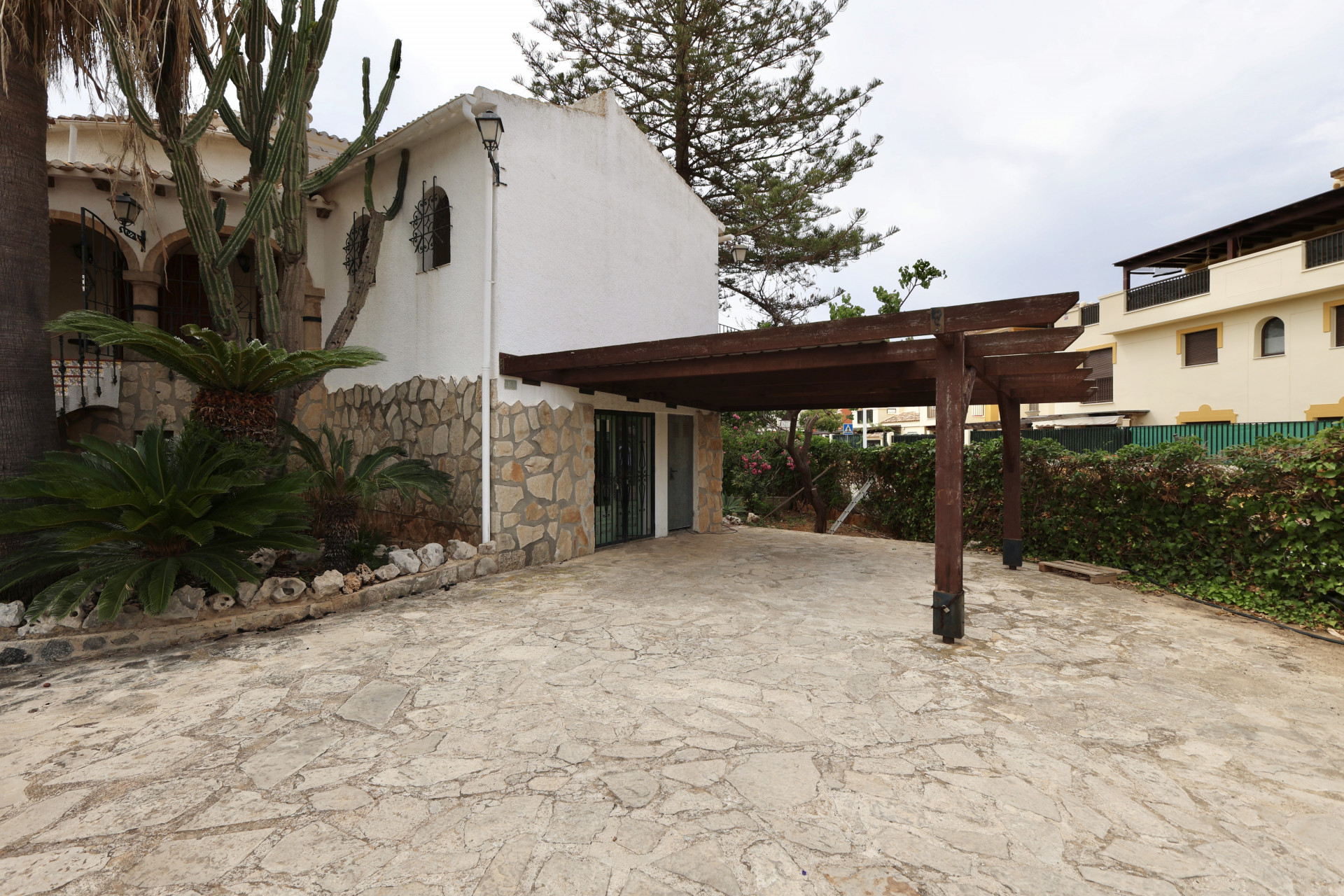 Villa entrance featuring irregular stone flooring and a covered garage with a wood structure.