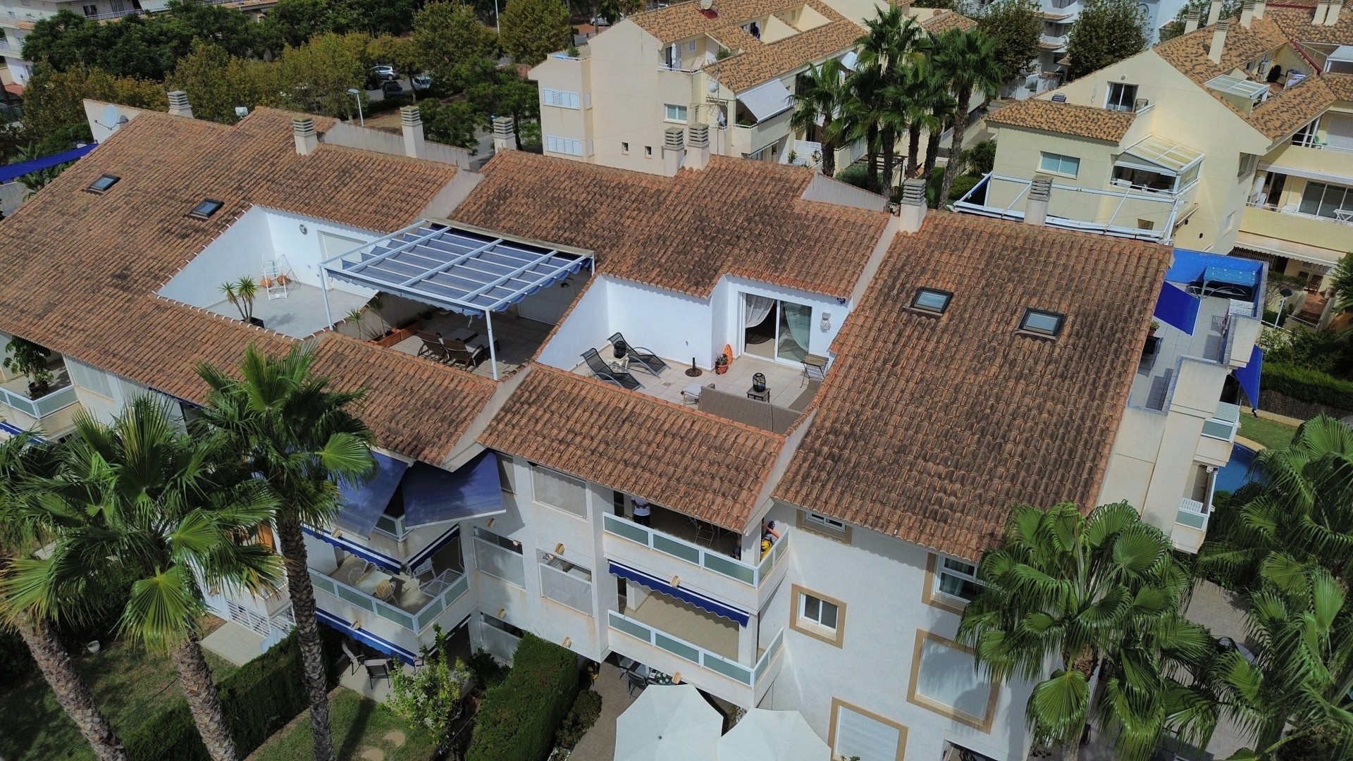 Aerial view of the duplex penthouse featuring a sun terrace, awning, and terracotta roof tiles in Jávea.