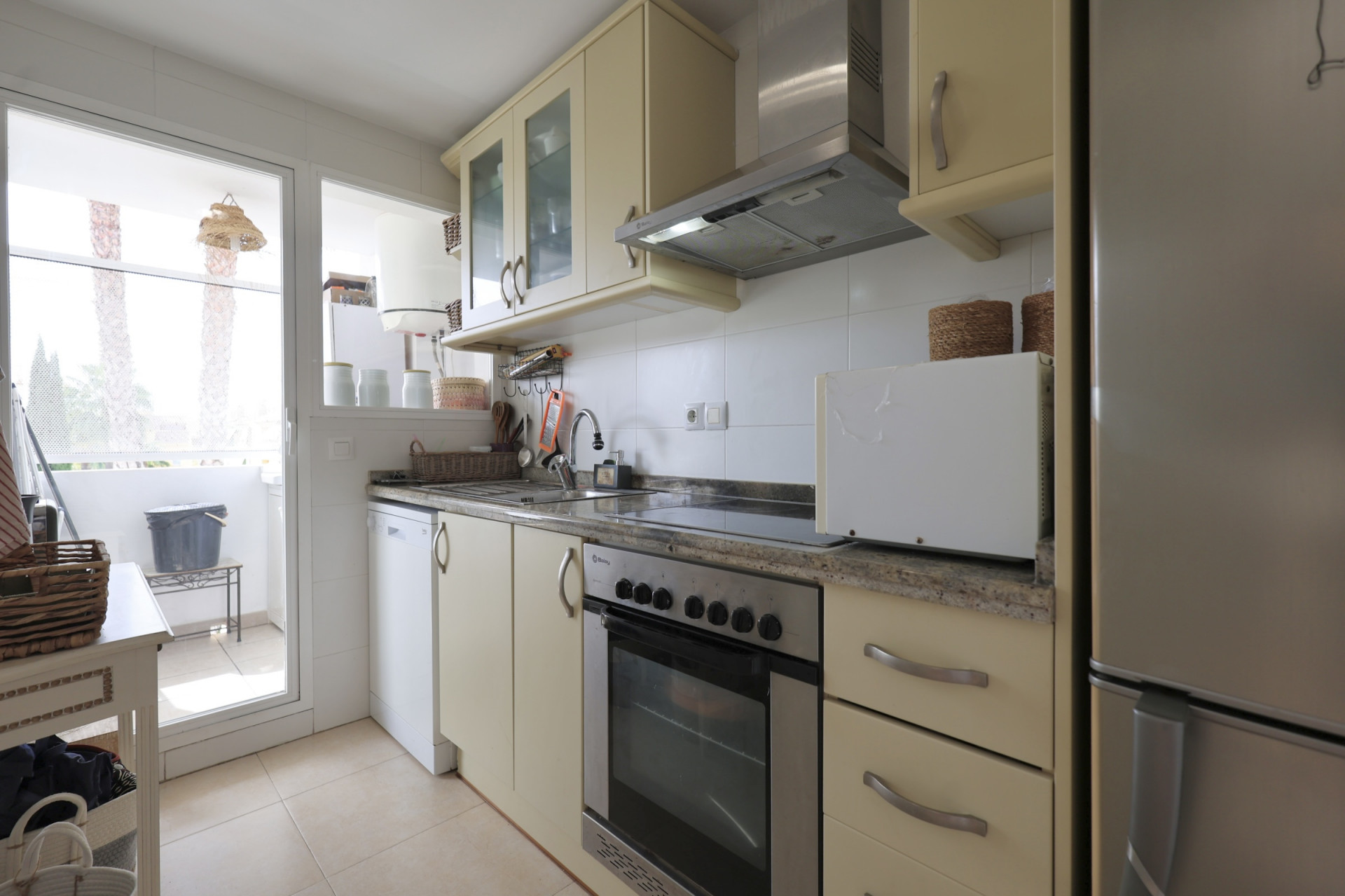 Bright kitchen featuring granite countertops, stainless steel appliances, and balcony access.