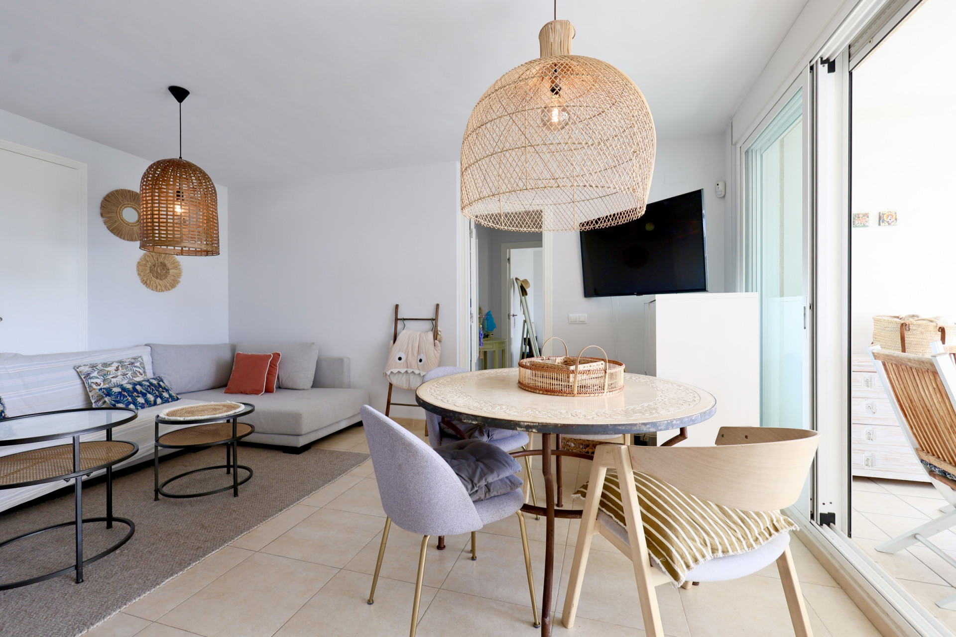 Bright living-dining area with wicker lamps and terrace access.