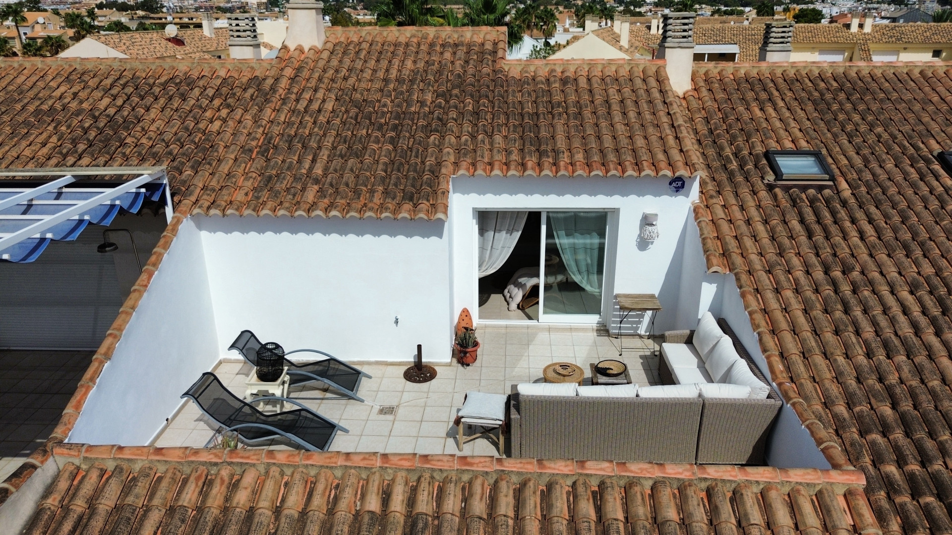 Elevated view of the sun-drenched terrace featuring outdoor furniture and interior access.