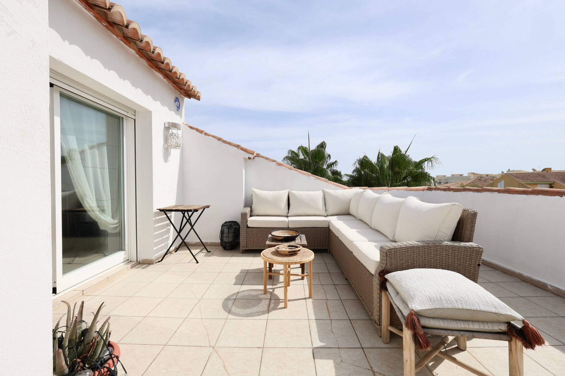 Sunny terrace featuring rattan furniture and partial horizon views.