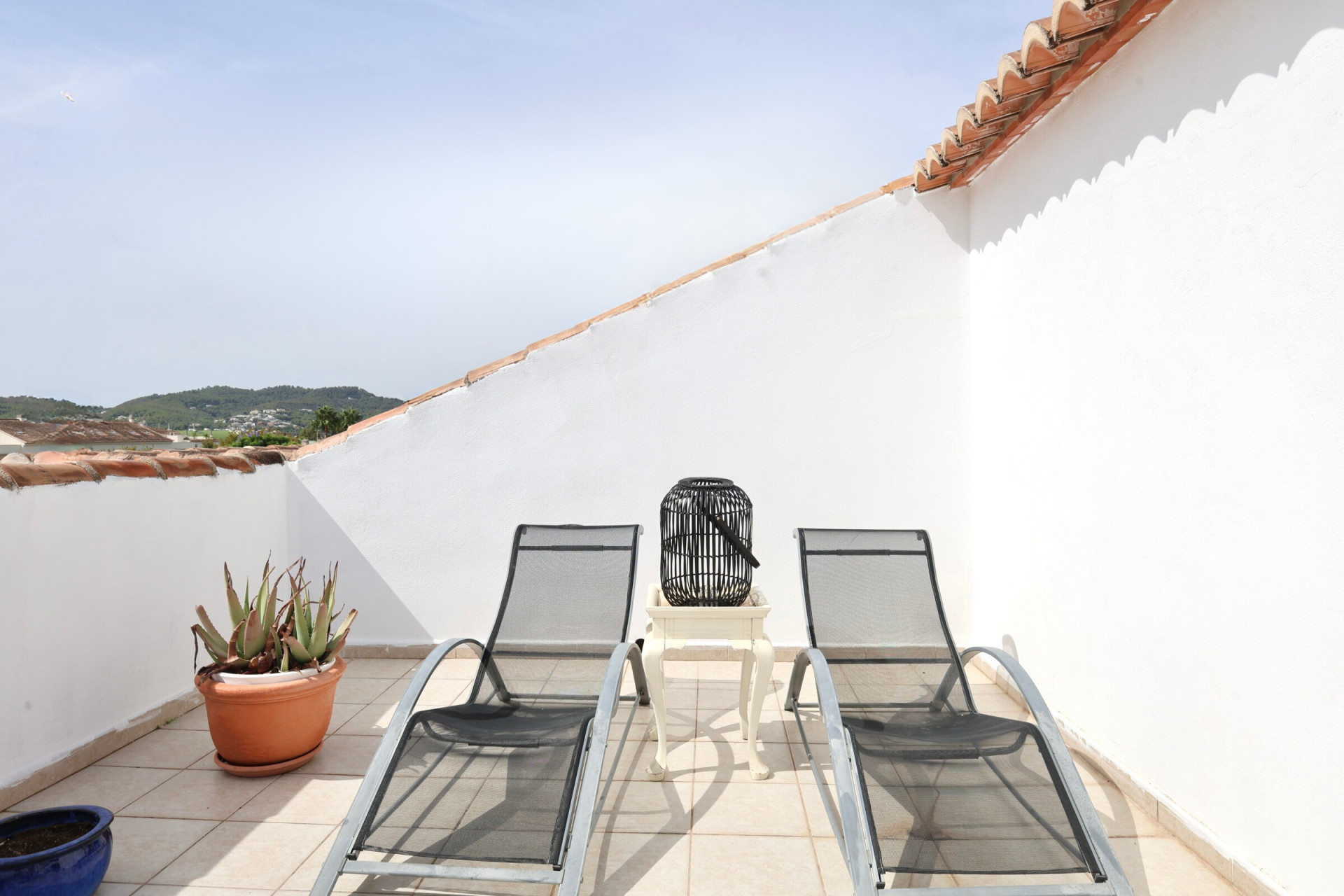 Terrace featuring two metal sun loungers, side table, and mountain views.