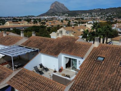 Aerial view of the solarium terrace with awning and outdoor furniture, surrounded by tiled roofs.