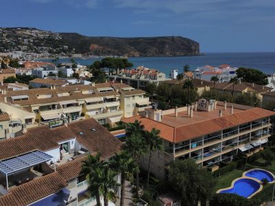 Aerial view of the urbanization with a pool and residential buildings with red roofs near the Jávea coast.