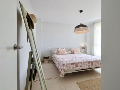 Bright bedroom featuring a double bed with marine-themed bedding and a wicker pendant lamp.