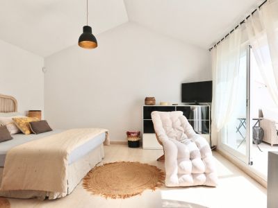 Bright bedroom featuring a rattan bed, jute rug, and terrace access.