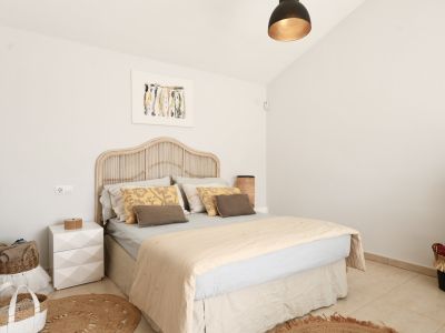 Bright bedroom featuring a rattan bed, round jute rug, and minimalist decor.