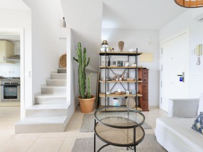 Bright interior featuring a white staircase, wood and metal shelving, and a rattan coffee table.