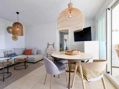Bright living-dining area with wicker lamps and terrace access.
