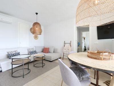 Bright living-dining room featuring a sectional sofa, wicker lamps, and a designer coffee table.