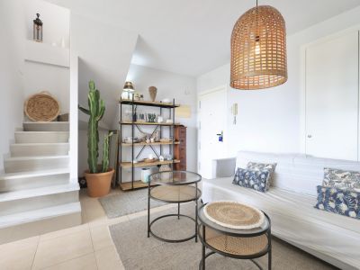 Bright living room with staircase to the duplex, minimalist decor, and a wicker pendant lamp.