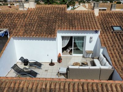 Elevated view of the sun-drenched terrace featuring outdoor furniture and interior access.