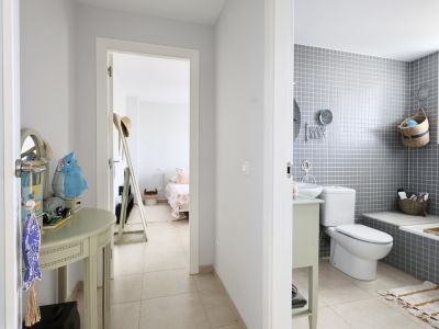 Hallway detail with decorative console table and view into bathroom with gray tiles and bedroom in the background.
