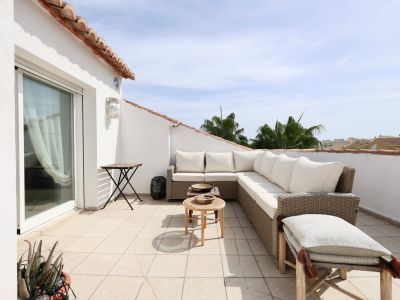 Sunny terrace featuring rattan furniture and partial horizon views.