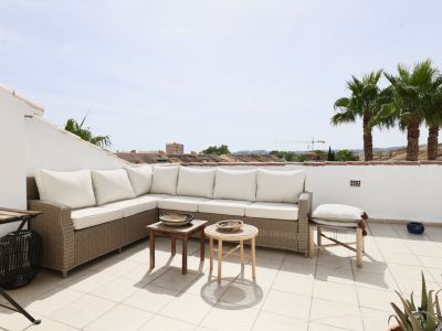 Terrace featuring a wicker sectional sofa with white cushions, overlooking palm trees and rooftops.