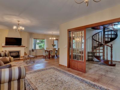 Open-plan living and dining area featuring a fireplace, tiled floors, and a distinctive wooden spiral staircase accessed via glass-paneled sliding doors.
