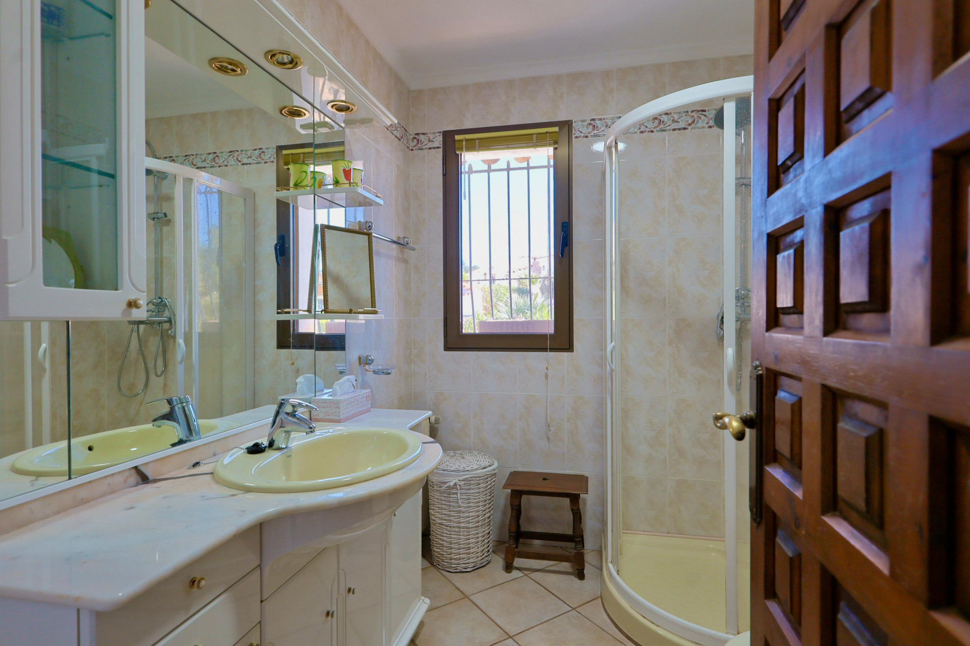 Bathroom detail with yellow sink, corner shower, and carved wood door.