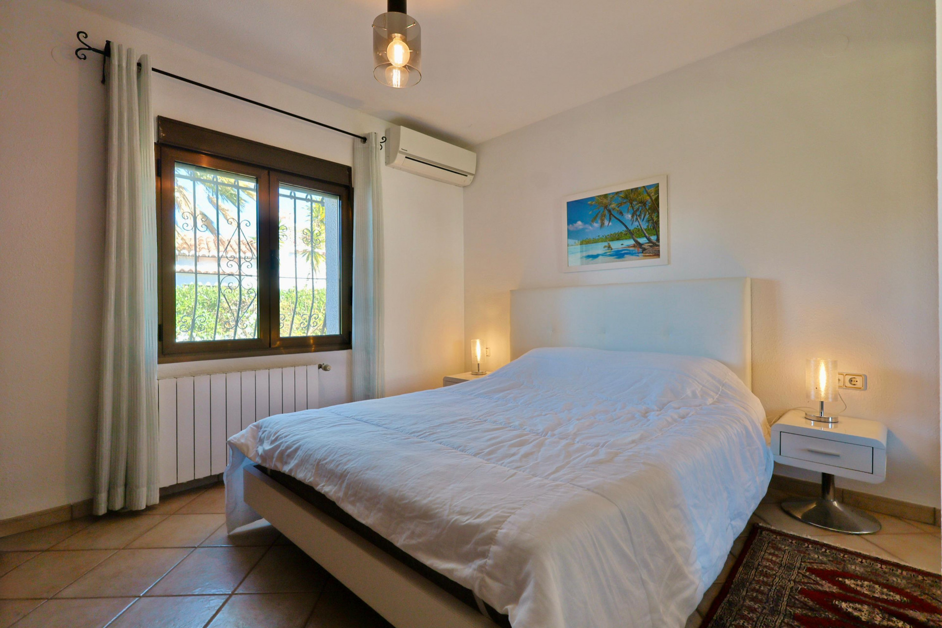 Bright bedroom featuring a double bed, modern bedside tables, and a window with exterior views.