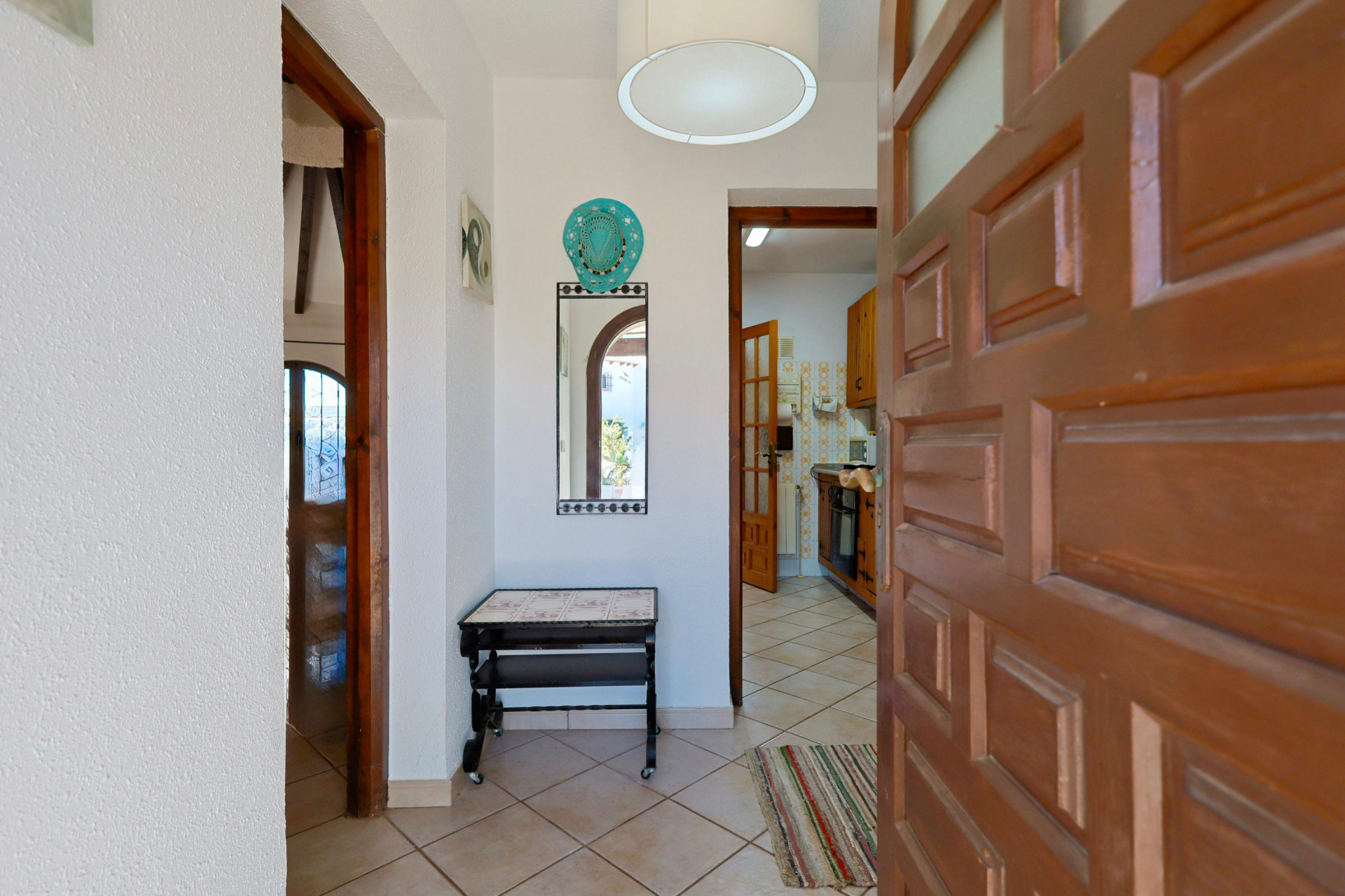 Bright entryway featuring a decorative mirror and a solid wood door ajar, leading to the kitchen.