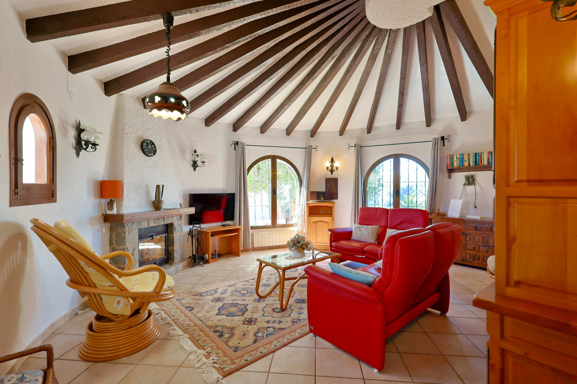 Circular living room featuring exposed wood beams and a stone fireplace.