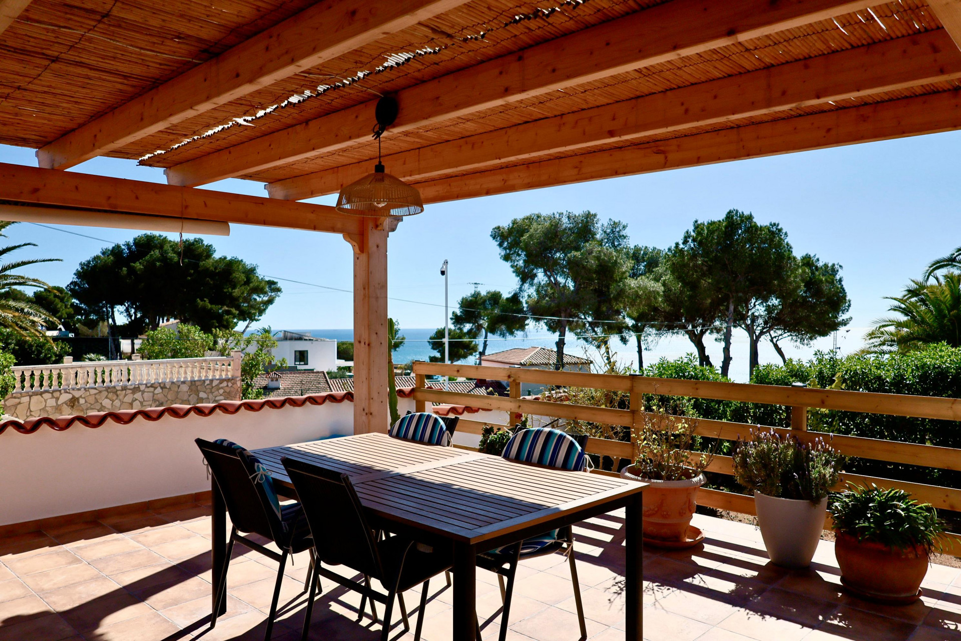 Covered terrace with dining table and sea views in Jávea.