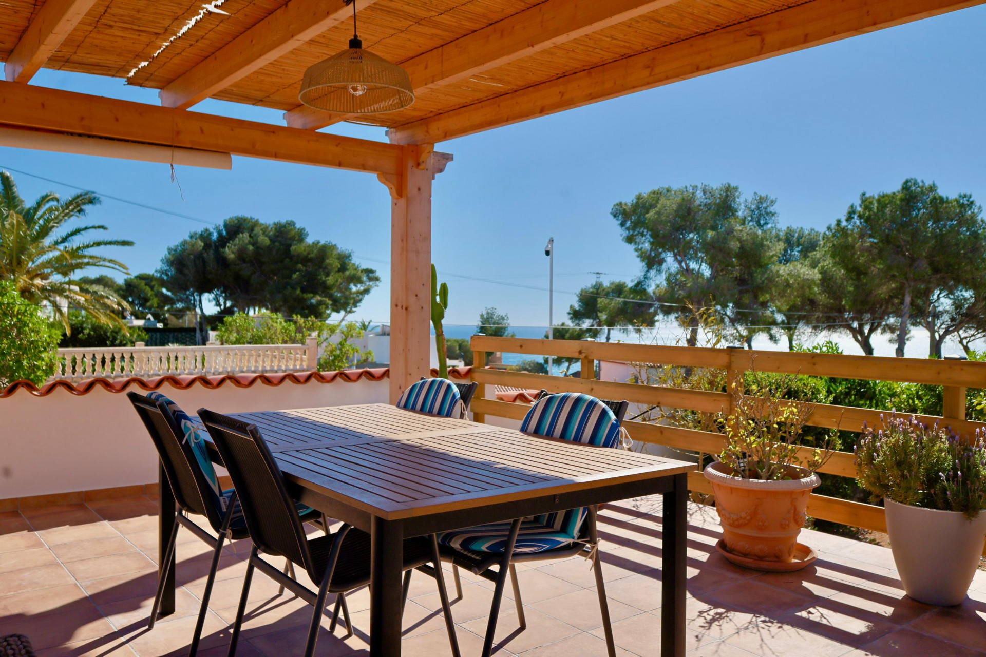 Covered terrace with dining table and views of the Mediterranean Sea.