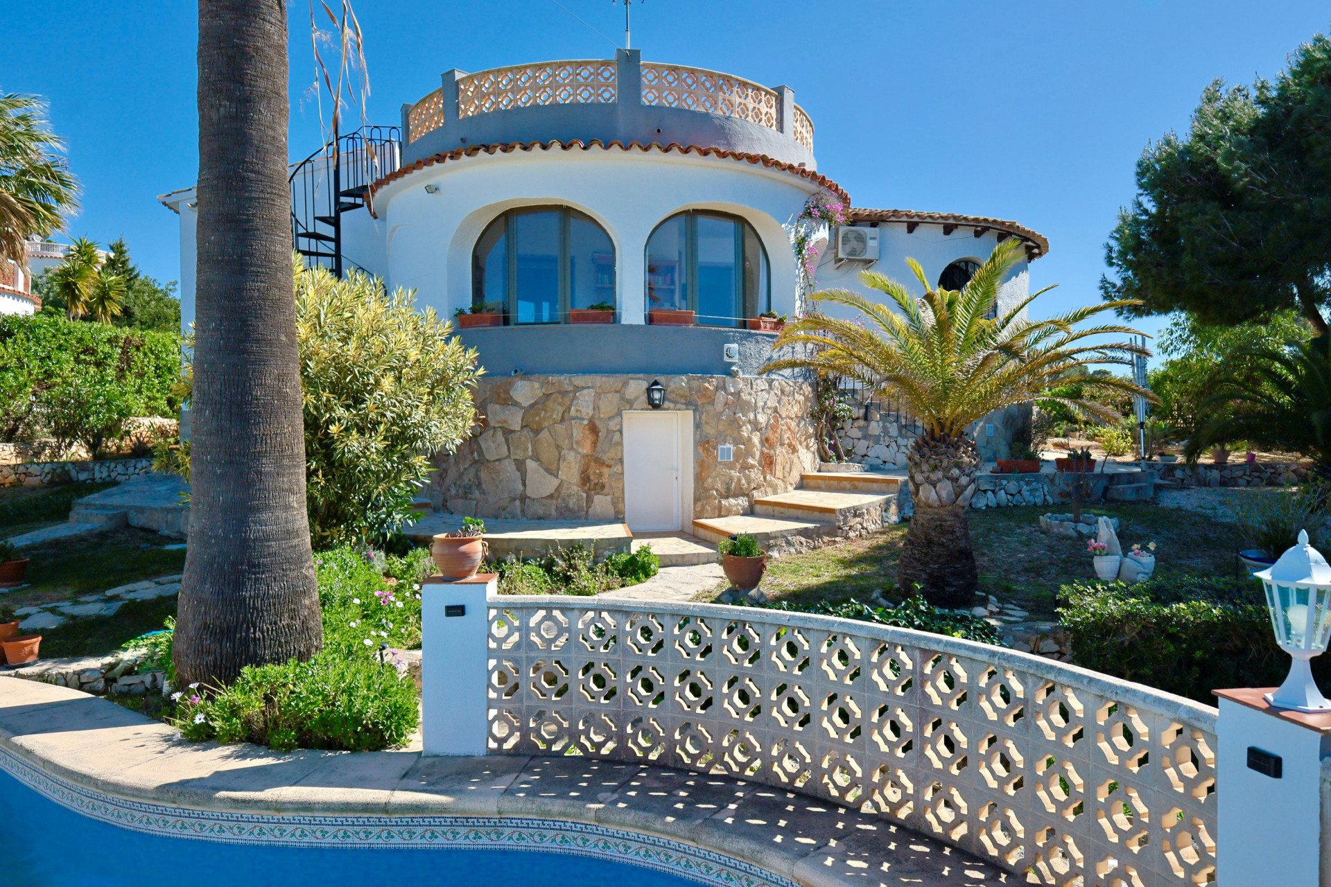 Exterior view of the villa with pool and stone facade, surrounded by Mediterranean gardens.