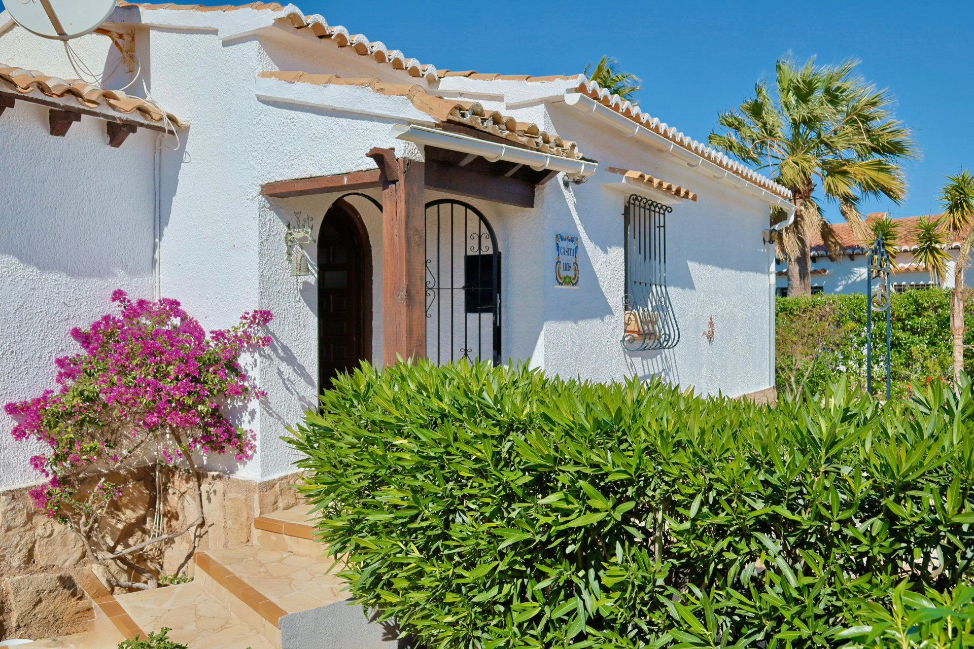 Mediterranean villa facade with bougainvillea and wood details.