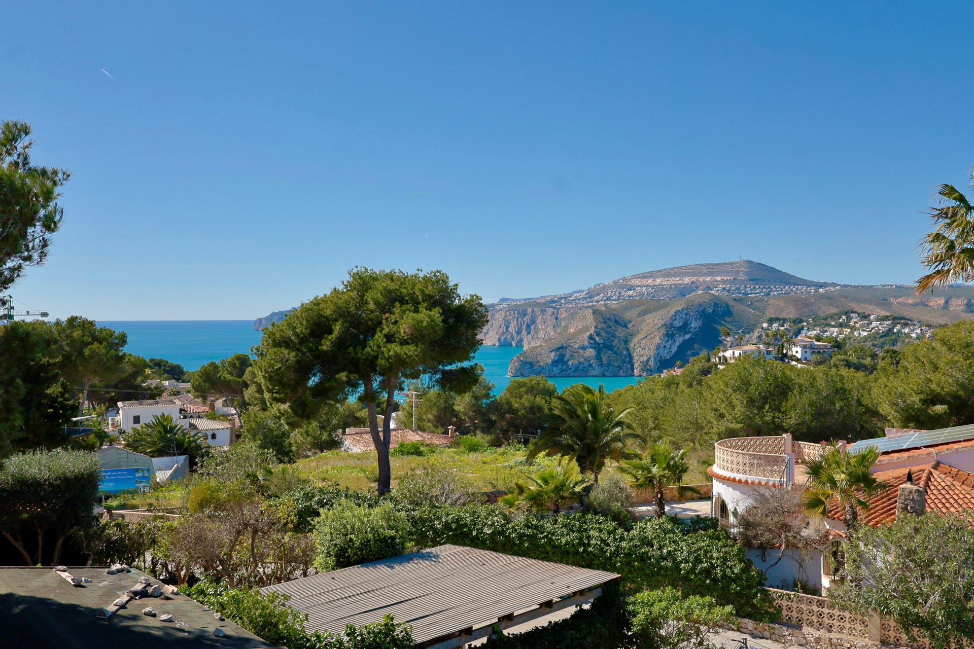 Panoramic view of Jávea coast and mountain from the terrace, featuring Mediterranean vegetation.