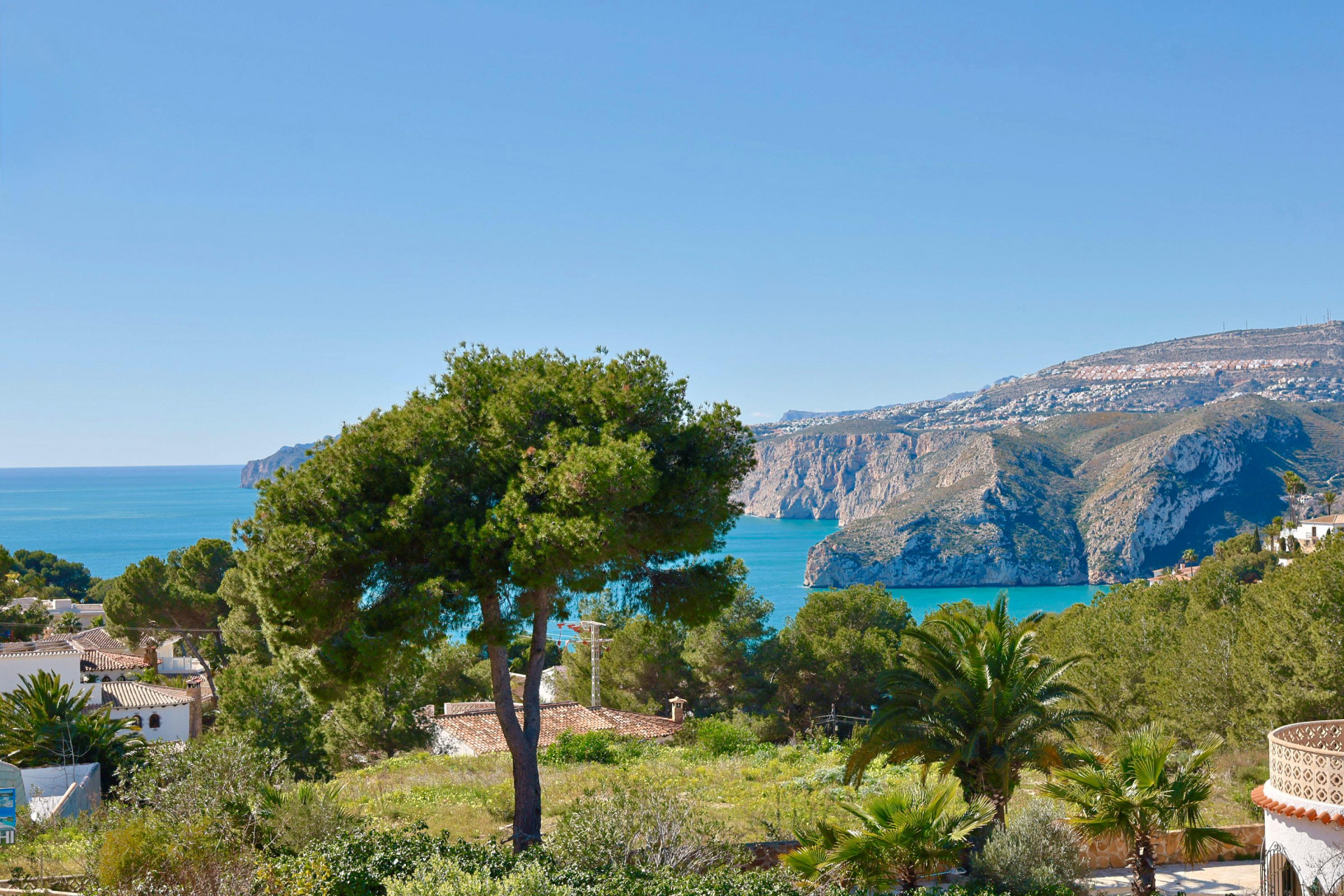 Panoramic view of Jávea featuring lush greenery and the Mediterranean Sea in the background.