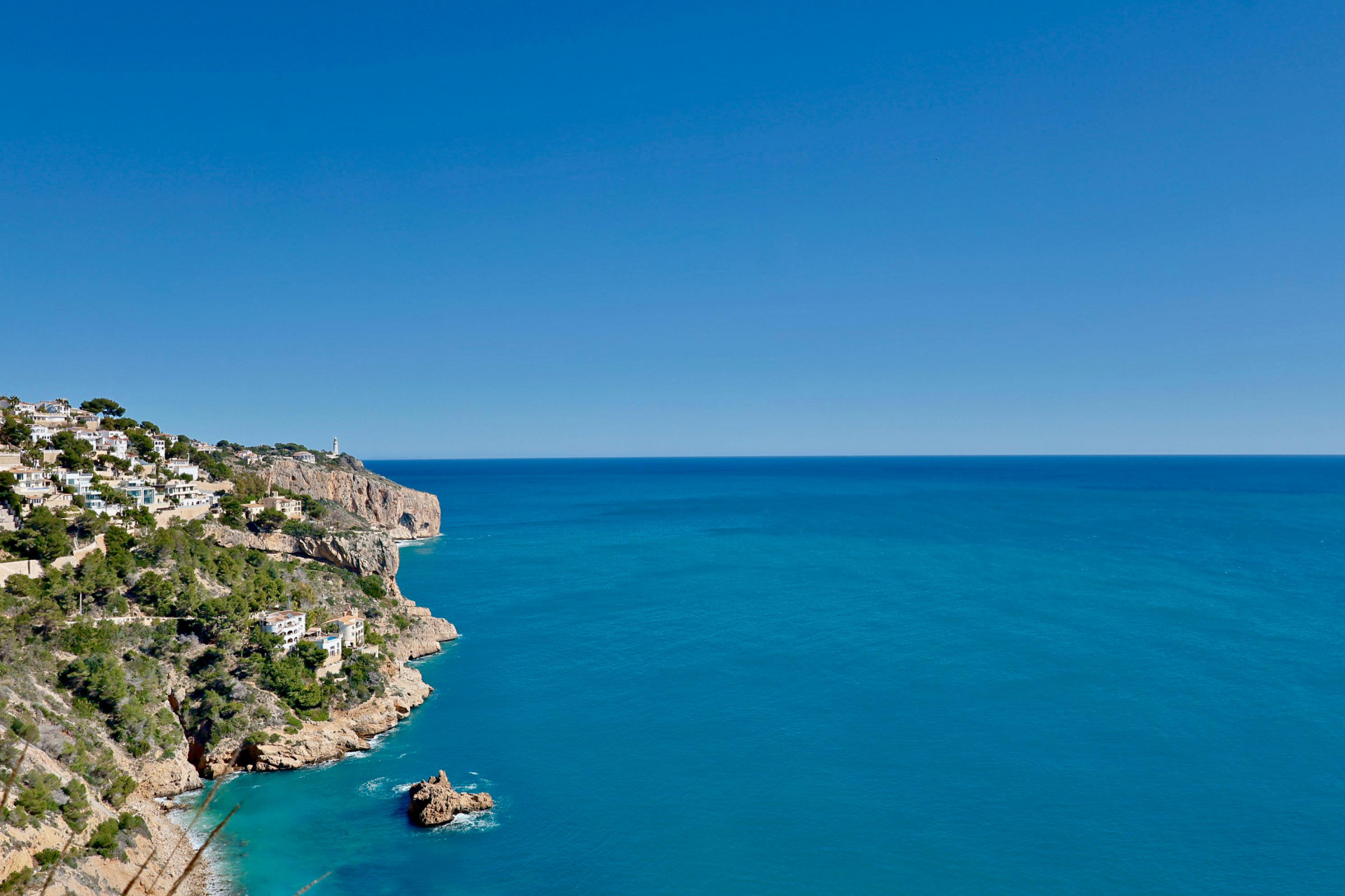 Panoramic view of Jávea's rocky coastline and the blue Mediterranean Sea.