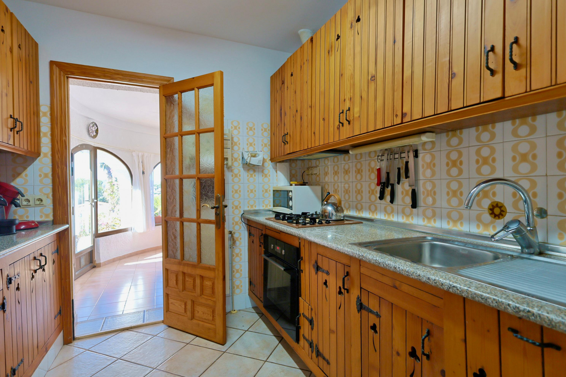 Rustic kitchen featuring wood cabinetry and access to a bright living room with large windows.