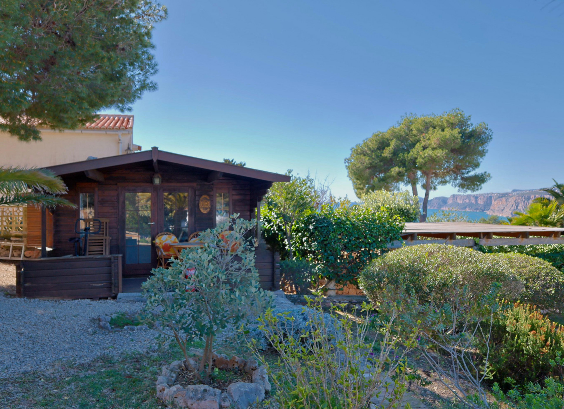 View of the wooden cabin, featuring a Mediterranean garden and sea views in Jávea.