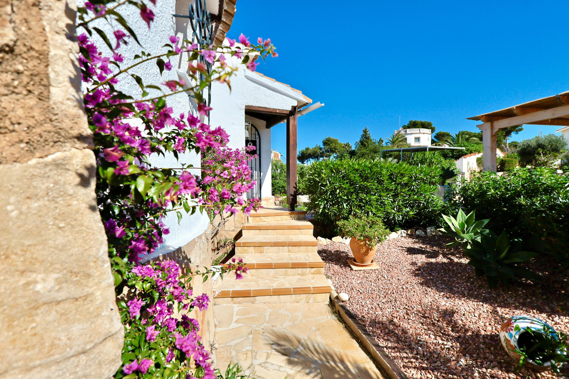 Villa entrance featuring fuchsia bougainvillea and gravel garden.