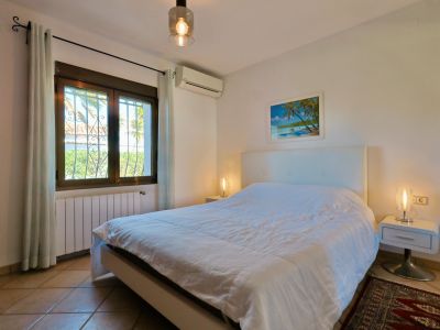 Bright bedroom featuring a double bed, modern bedside tables, and a window with exterior views.